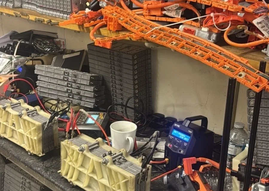 Workshop shelf with Japanese-made hybrid battery packs and orange high-voltage parts